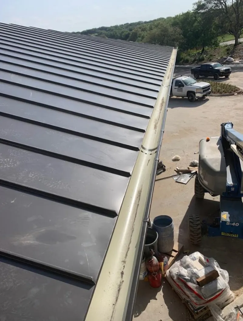 Standing seam panel and gutter detail on a metal roofing jobsite in Groton